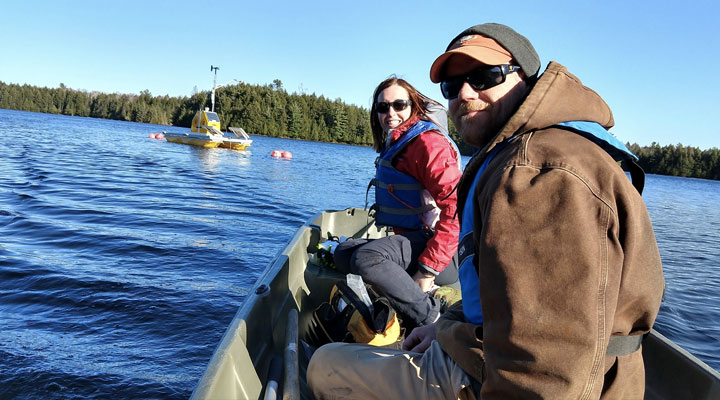 Photo: Two ecologists in a boat collecting ecological samples