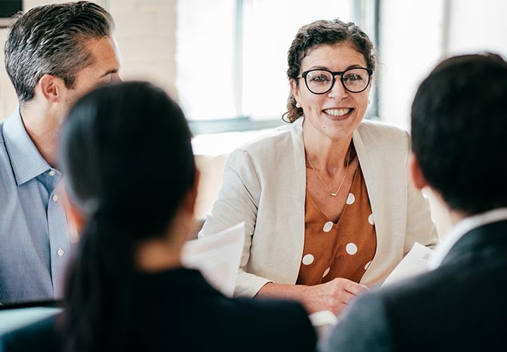 alt= close up of a women smiling during a meeting in an office