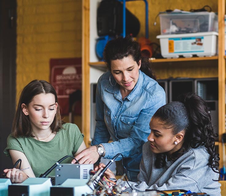 stem-education-feature-call-out alt = two female stem students working on a robotic with the help of their stem teacher