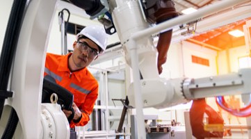 Photo: Engineer taking notes while examining machinery.