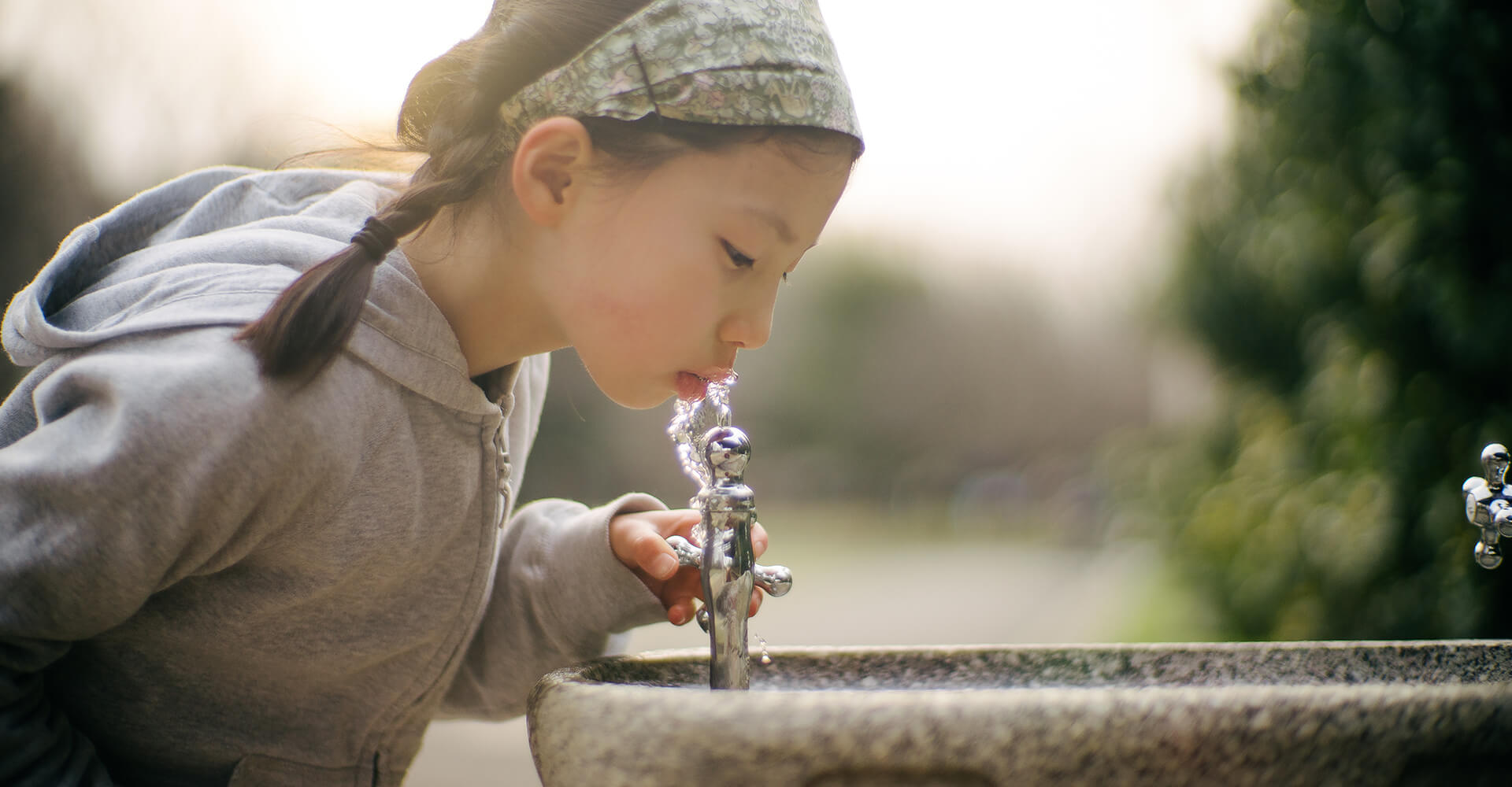 alt = little girl drinking pfas free water from a fountain