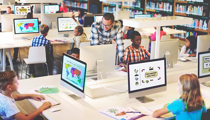 alt= stem teacher helping a group of stem students in a computer lab