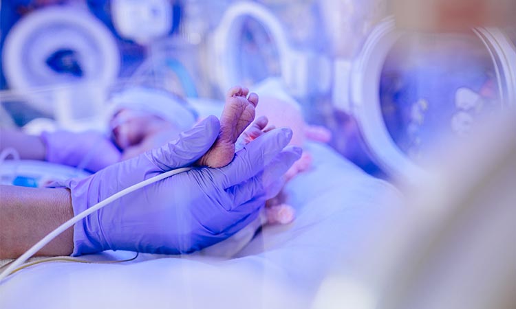 alt=a doctor holding a baby's foot in a aerosol delivery system