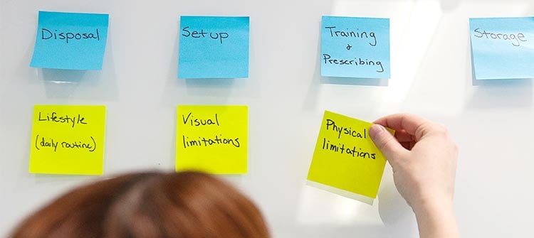 balance-product-design-1 alt = an hcd member putting post it notes on a whiteboard