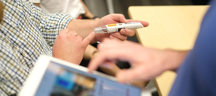 tangible-user-inouts-2 alt= a person using an autoinjector at a doctors office