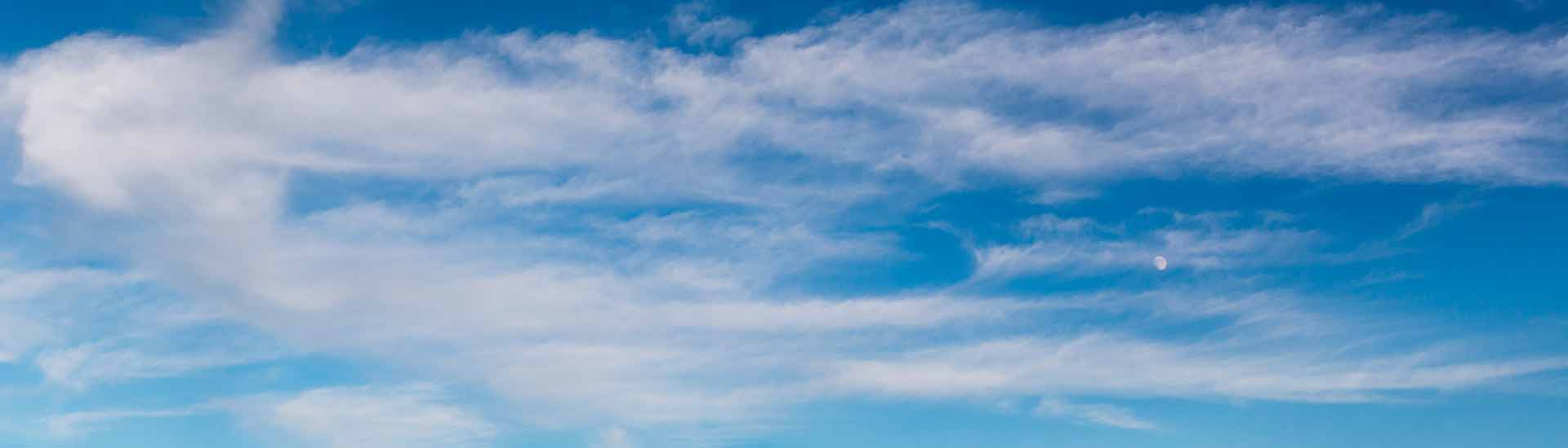 Photo: Clouds in a blue sky with the moon in the background