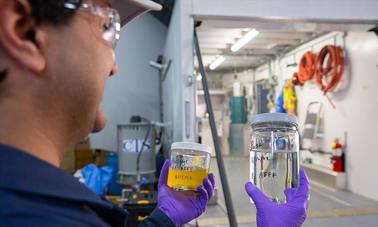 Photo: pfas annihilator technician hold a jar of contaminated and decontaminated pfas