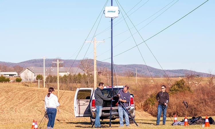 alt = battelle employees setting up a test of the ravenstar antenna