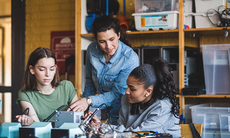 Photo: Teacher and students examining electronics