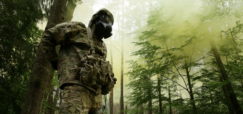 Photo: United States warfighter in NBC gear and mask in forest under CBRN attack