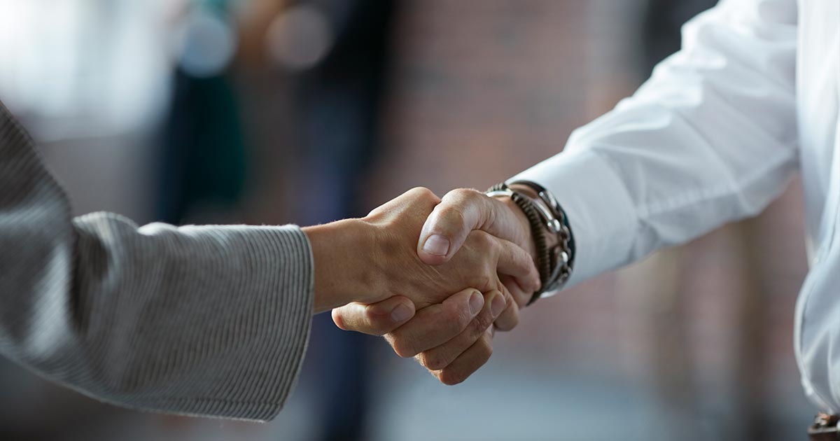 alt= two business partners shaking hands