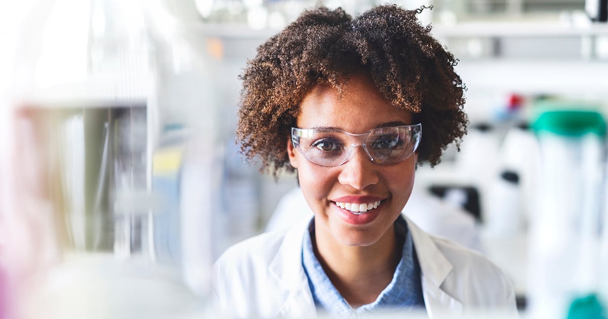 Photo: African American scientist smiling in lab with goggles on