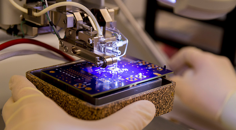 test-evaluation-microelectronics-inspection Photo: Battelle Hardware assurance expert examining hardware for threats