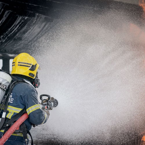 Image: Airport firefighter spraying PFAS-contaminated AFFF foam on a airplane fire