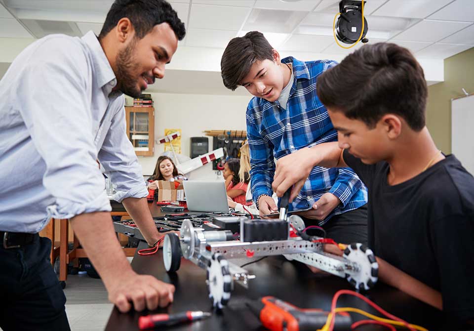 Photo: stem educator helping two students with engineering project