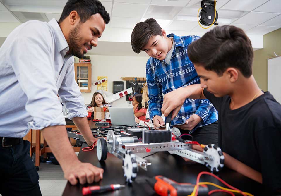 Stem educator helping two students with engineering project Photo: stem educator helping two students with engineering project