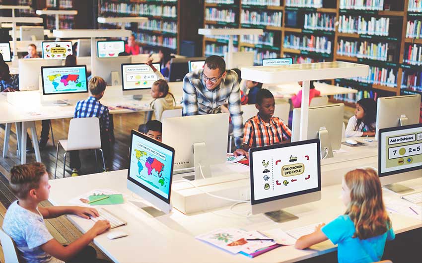 STEMx Network call out Photo: STEM educator helping students with a STEM project in a computer lab