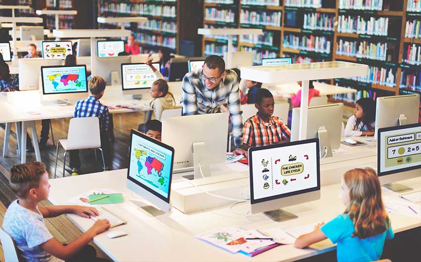 Photo: STEM educator helping students with a STEM project in a computer lab