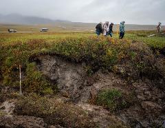 Photo: Students walk along the edge of a large permafrost gully