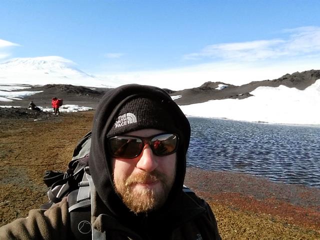 Photo: Eric with colleagues sampling mats near ponds on Cape Royds on Ross Island, Antarctica. Mt. Erebus is in the background. 